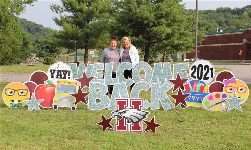 A group takes a photo in front of a welcome back sign